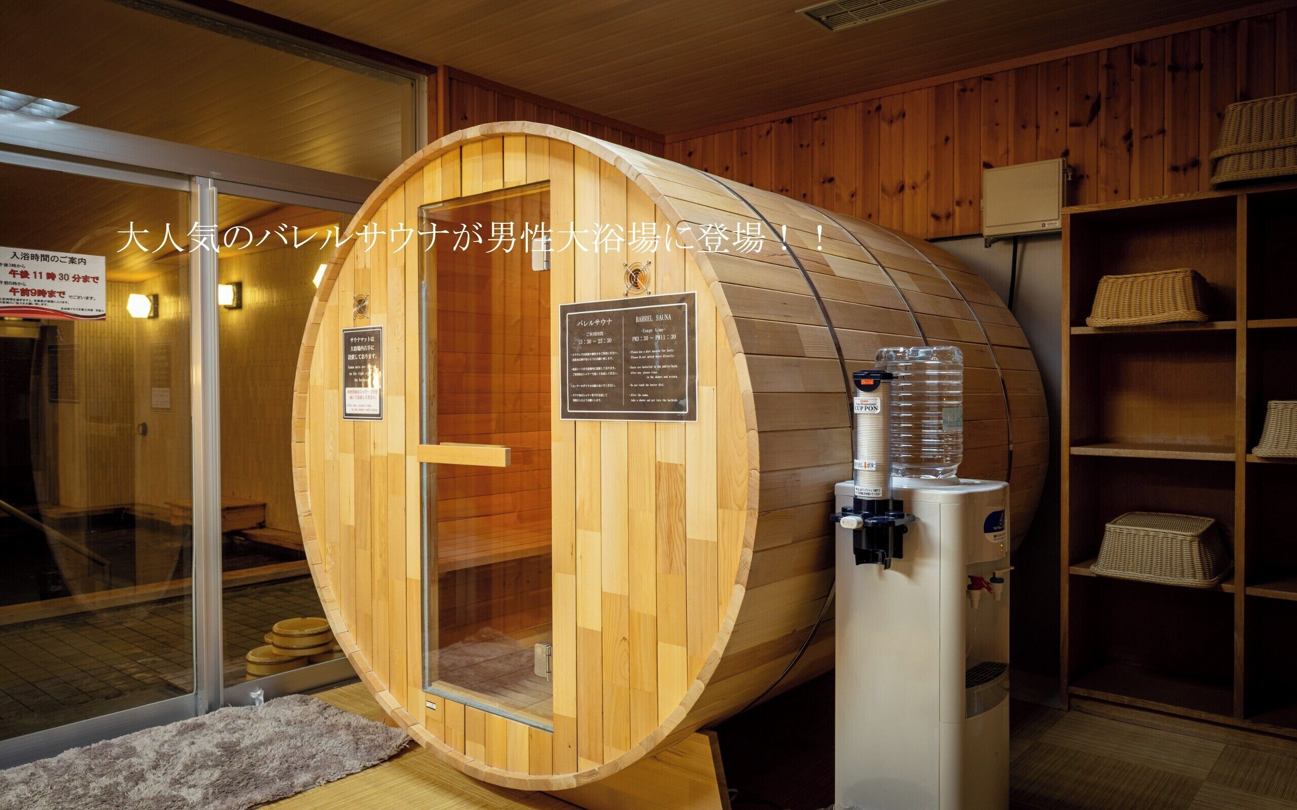 A wooden sauna with a glass door, a water dispenser, and wooden shelves with baskets.