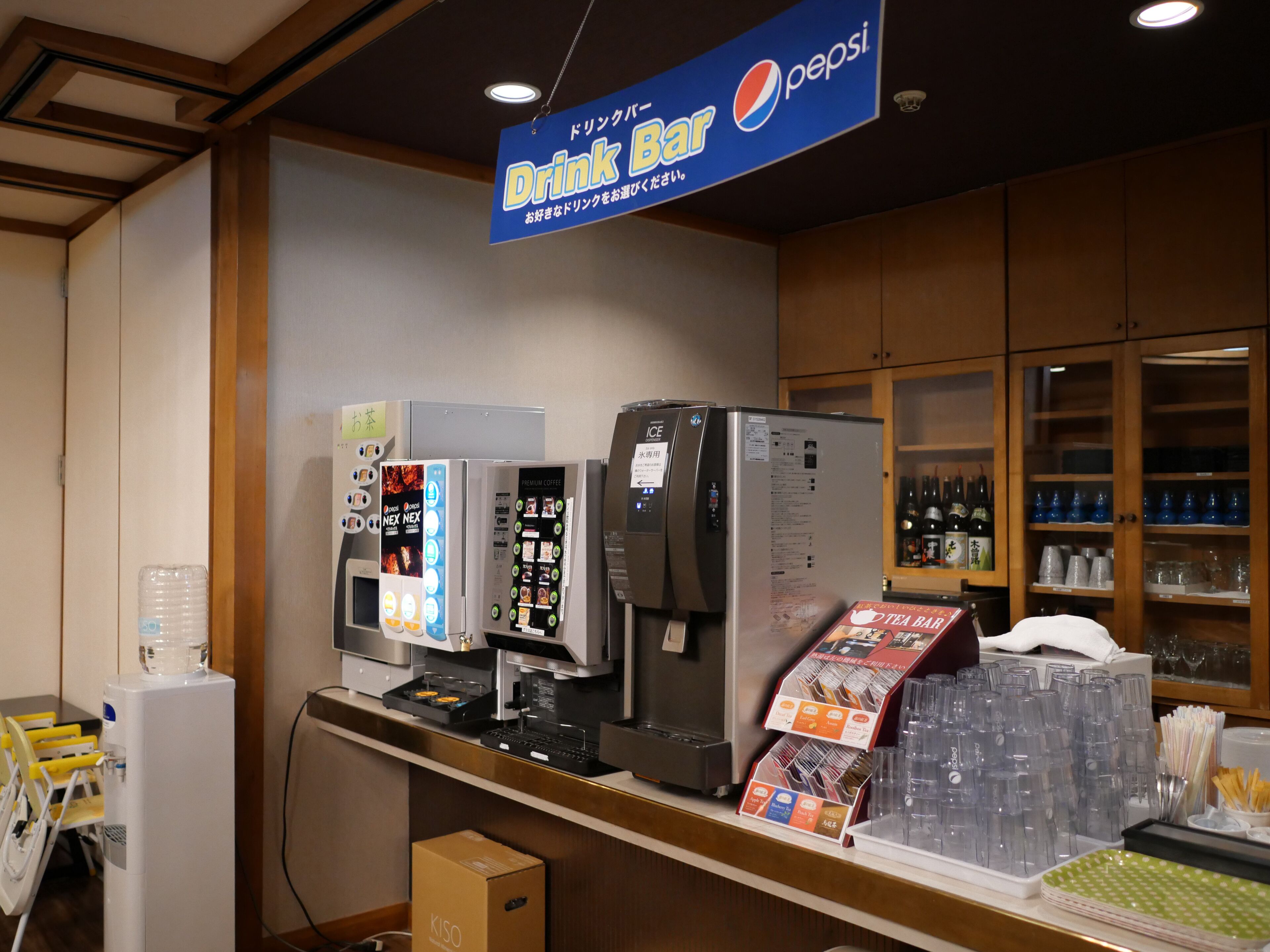 A drink bar area with a Pepsi sign, a coffee machine, and a refrigerator.