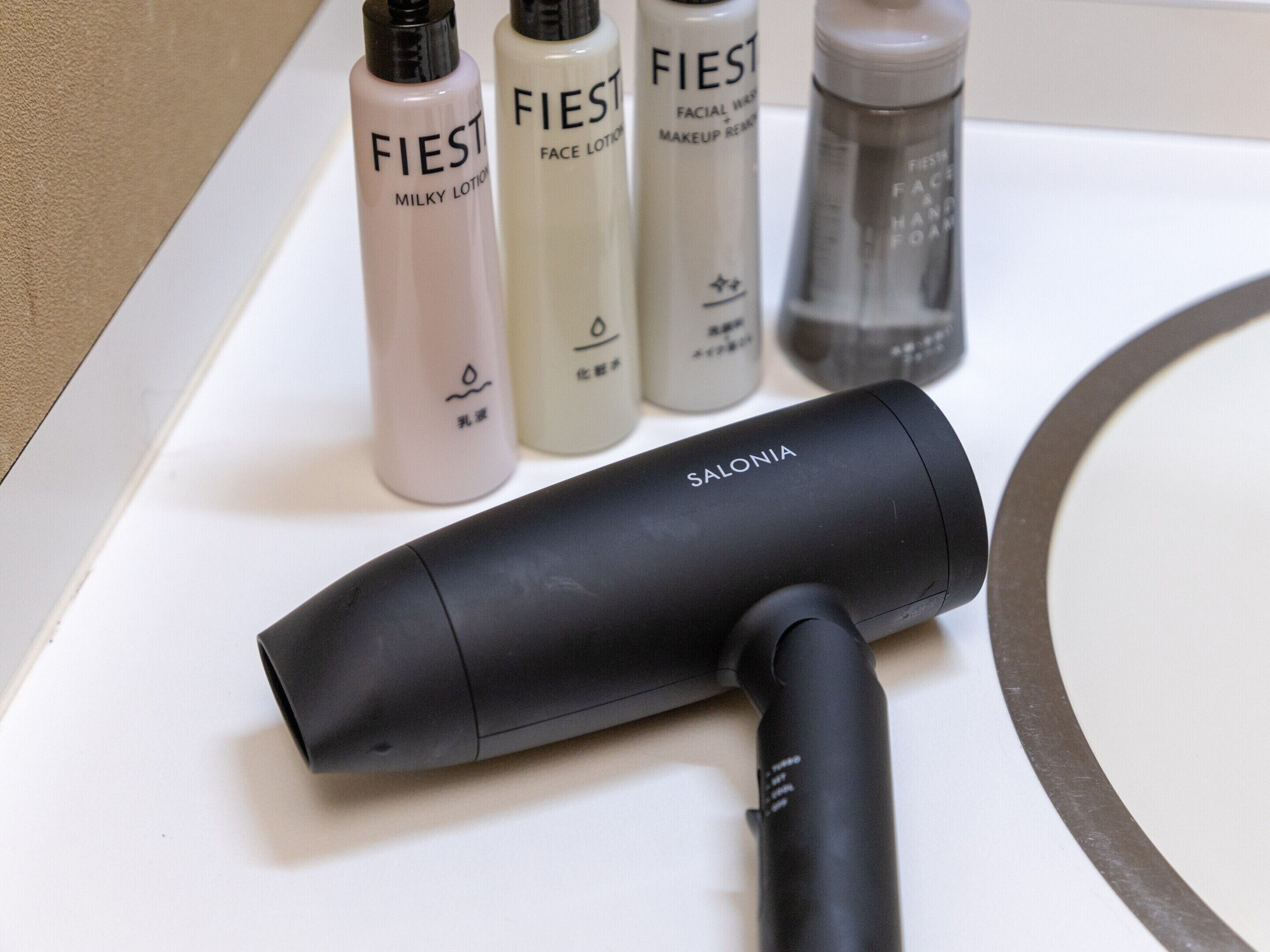 A hair dryer and three bottles of FIEST facial care products on a counter.