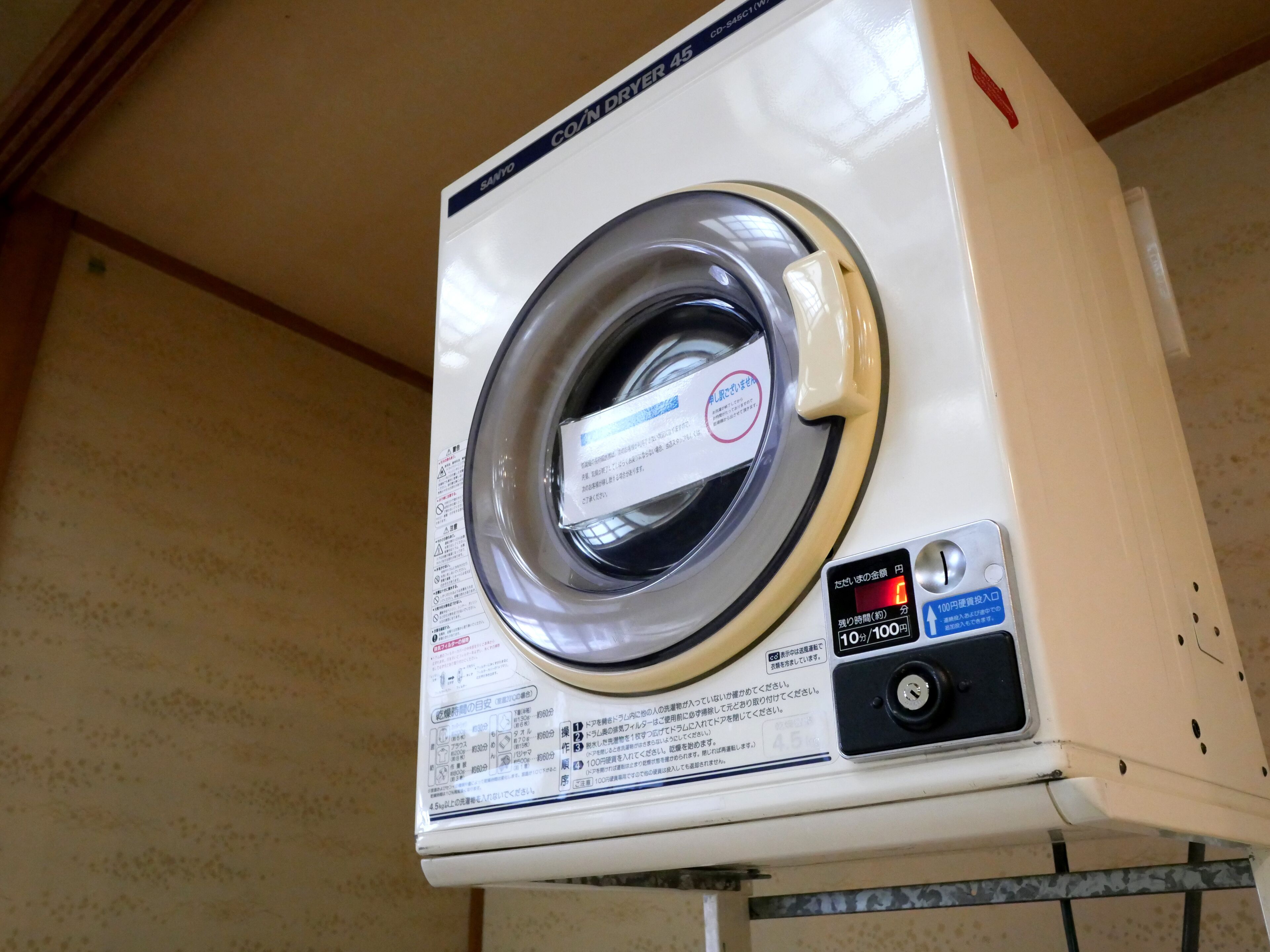 A white, wall-mounted, front-loading washing machine with a control panel and a label.
