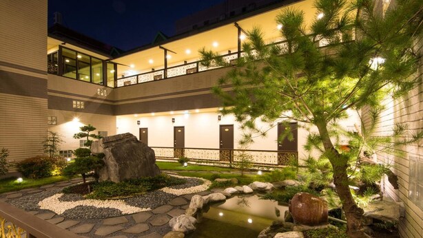 A well-lit courtyard with a koi pond, stone pathway, and a large rock centerpiece. - Dongdaemun Boutique Hotel (Hualien City)