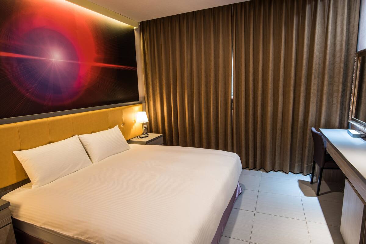 Une chambre d’hôtel avec un grand lit, un bureau et un téléviseur fixé au mur.