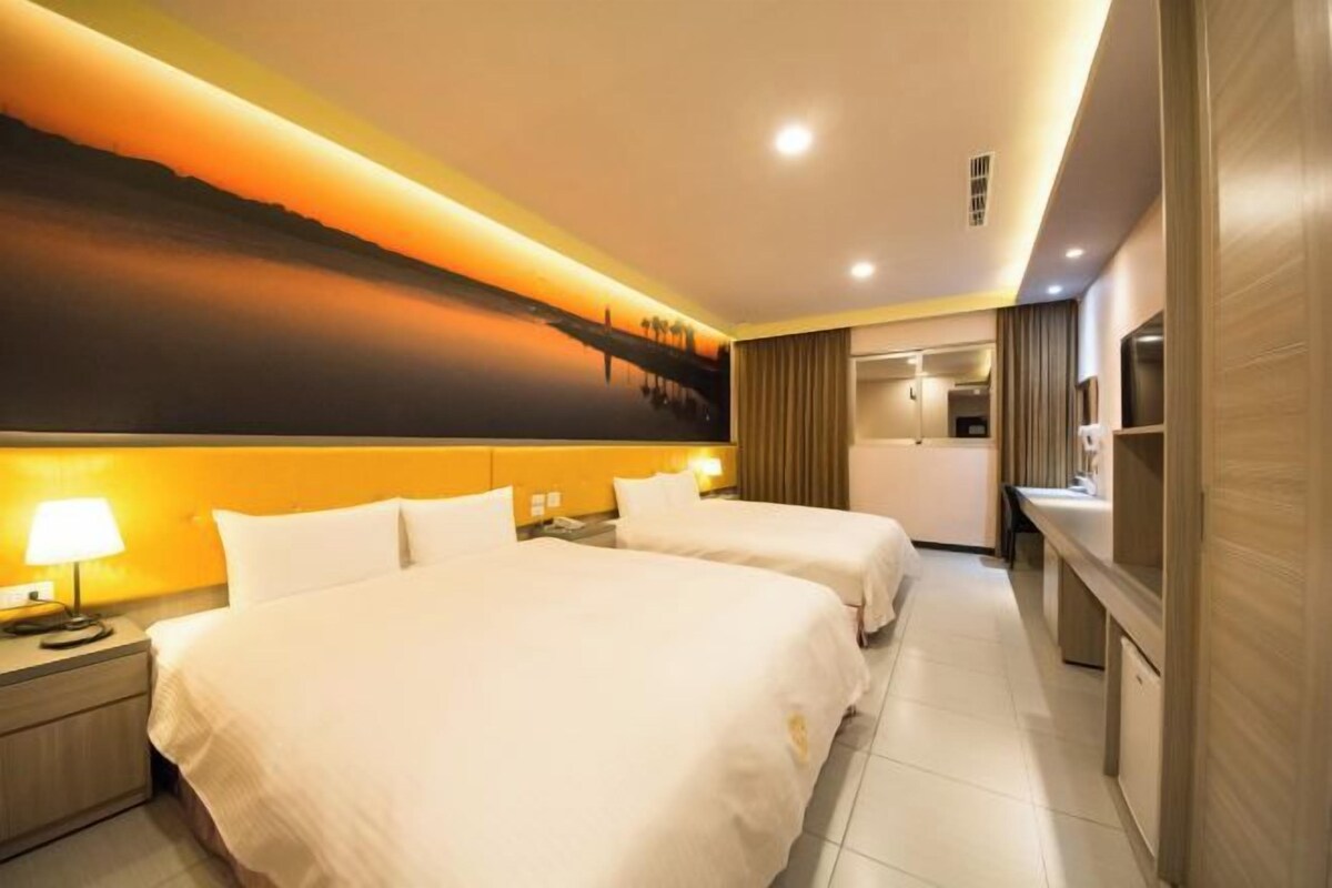 Une chambre d’hôtel avec deux lits, une grande fresque murale, un bureau et une salle de bain.