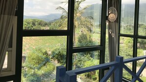Una habitación con amplios ventanales que ofrecen vistas a un jardín exuberante y montañas lejanas.