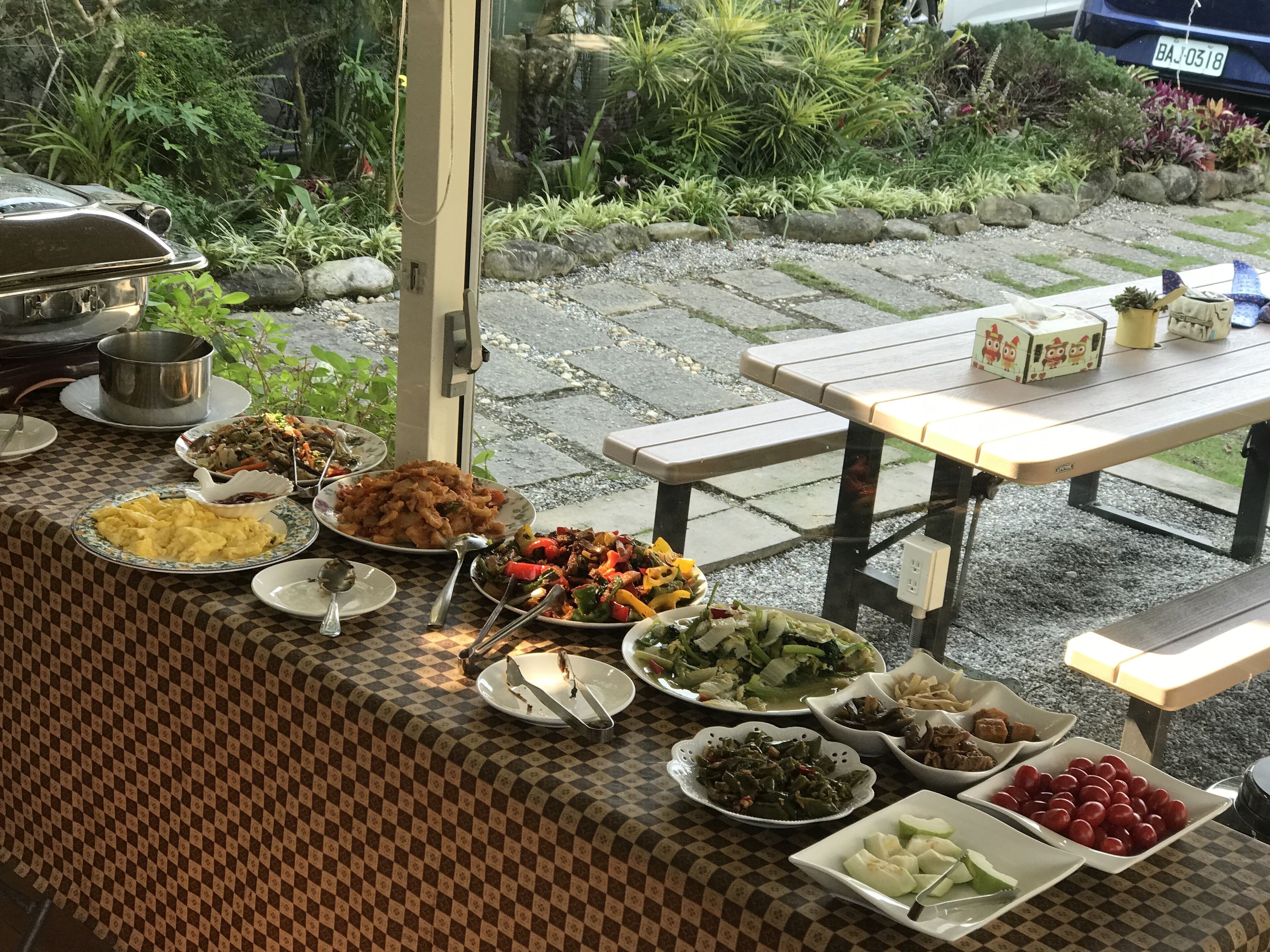 An outdoor dining area with a variety of dishes on a checkered tablecloth.