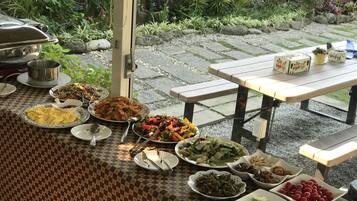 An outdoor dining area with a variety of dishes on a checkered tablecloth.