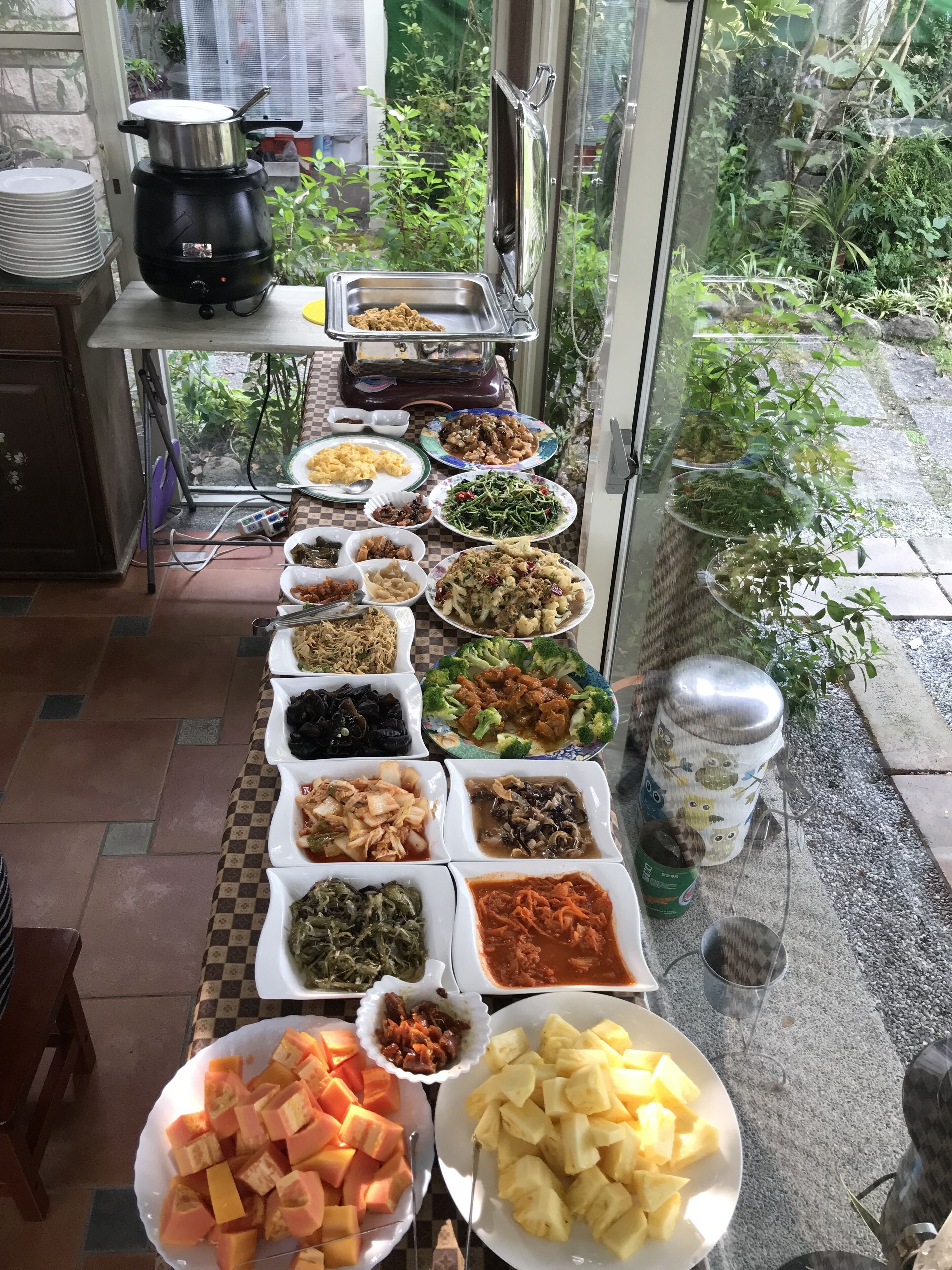 A buffet table with various dishes and a portable stove in the background.