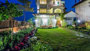 Una casa de dos pisos con un jardín cuidado y un balcón visible.
