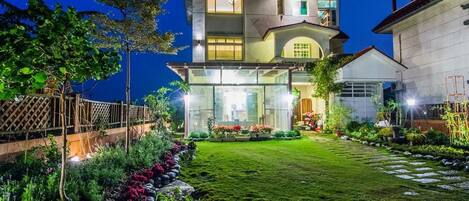A two-story house with a well-maintained garden and a visible balcony.