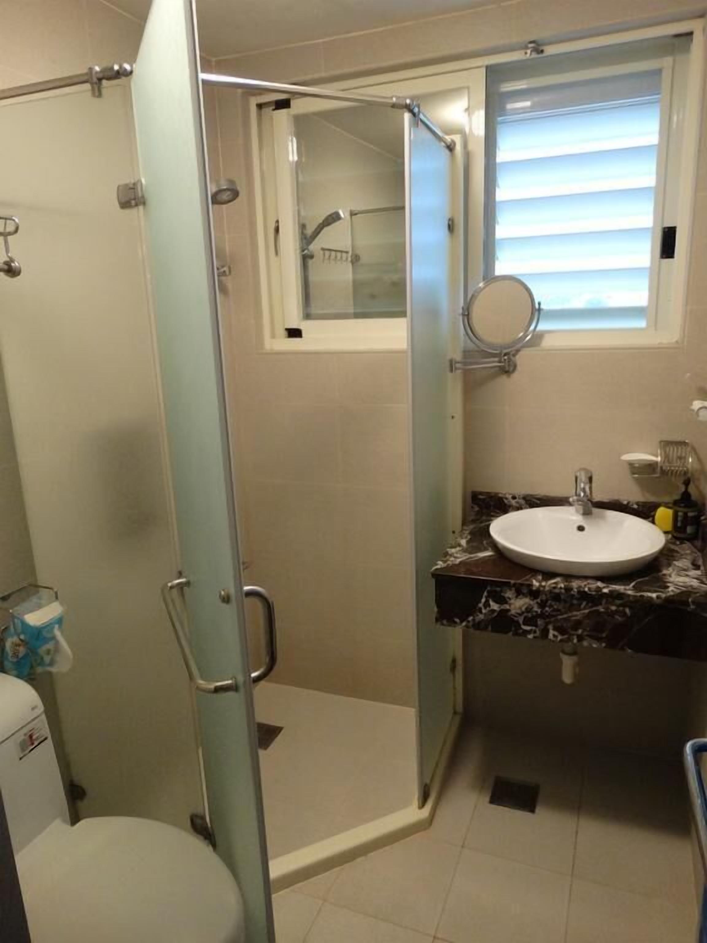 Un baño con ducha envuelta en vidrio, lavabo con espejo e inodoro.
