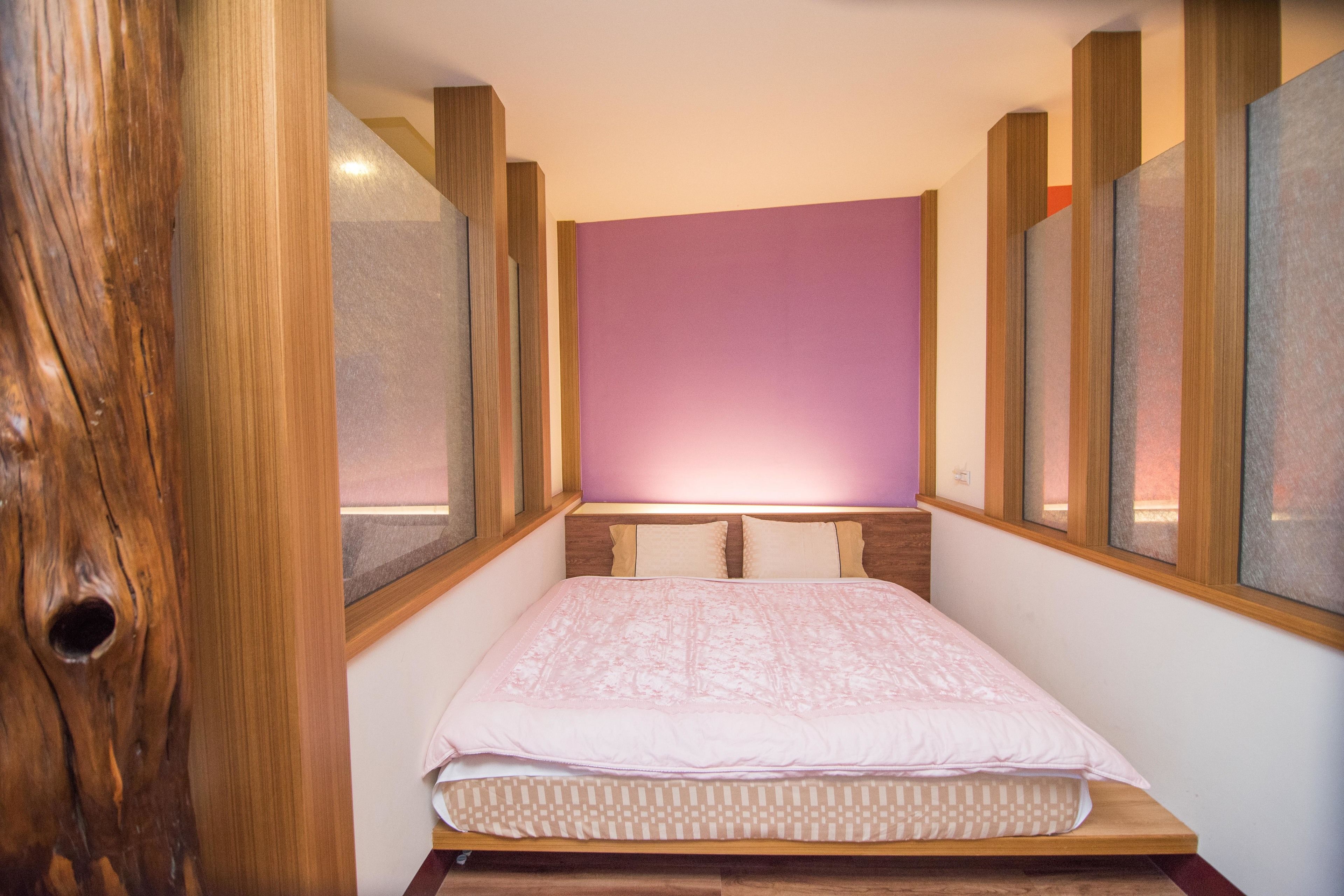 Une chambre à coucher avec une tête de lit en bois, un mur rose et une fenêtre donnant sur un beau paysage.