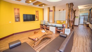 Une salle de spa moderne avec un plancher en bois, une grande table en bois, une table de massage et un grand miroir.