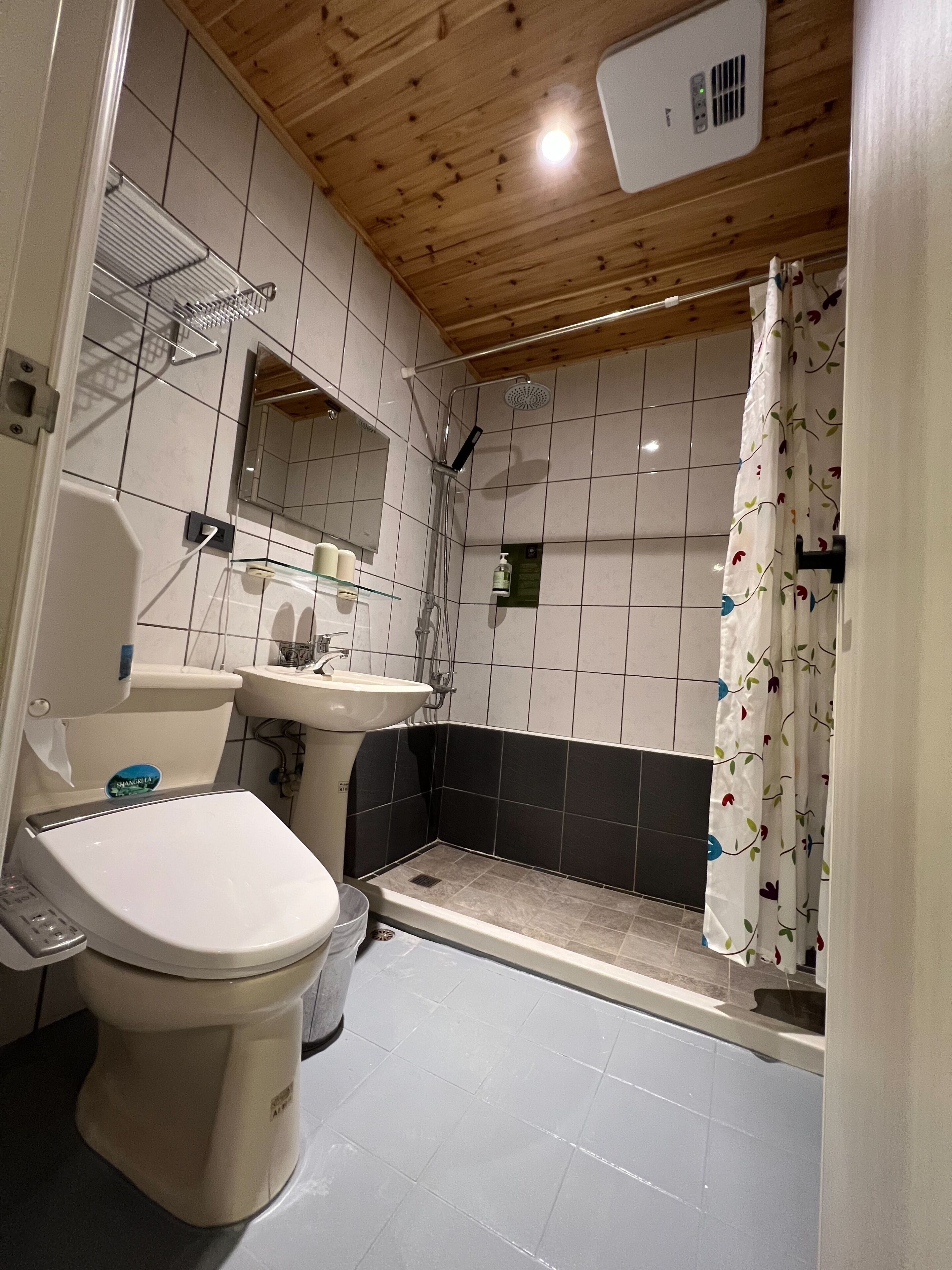 A small bathroom with a toilet, sink, shower, and a mirror.