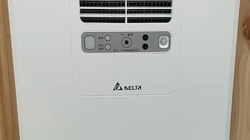 A white air conditioning unit with a control panel and a circular vent at the bottom.