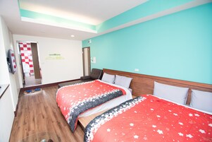 Quarto de hotel com duas camas, soalho de madeira, decoração de parede xadrez e porta para uma casa de banho.