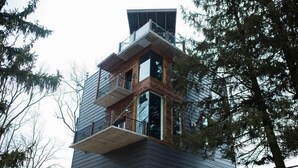 A modern multi-story building with a unique architectural design, featuring balconies and large windows. - The Dwell House (Sugarcreek)