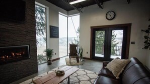 A cozy living room with a fireplace, a leather sofa, and a coffee table. - The Dwell House (Sugarcreek)