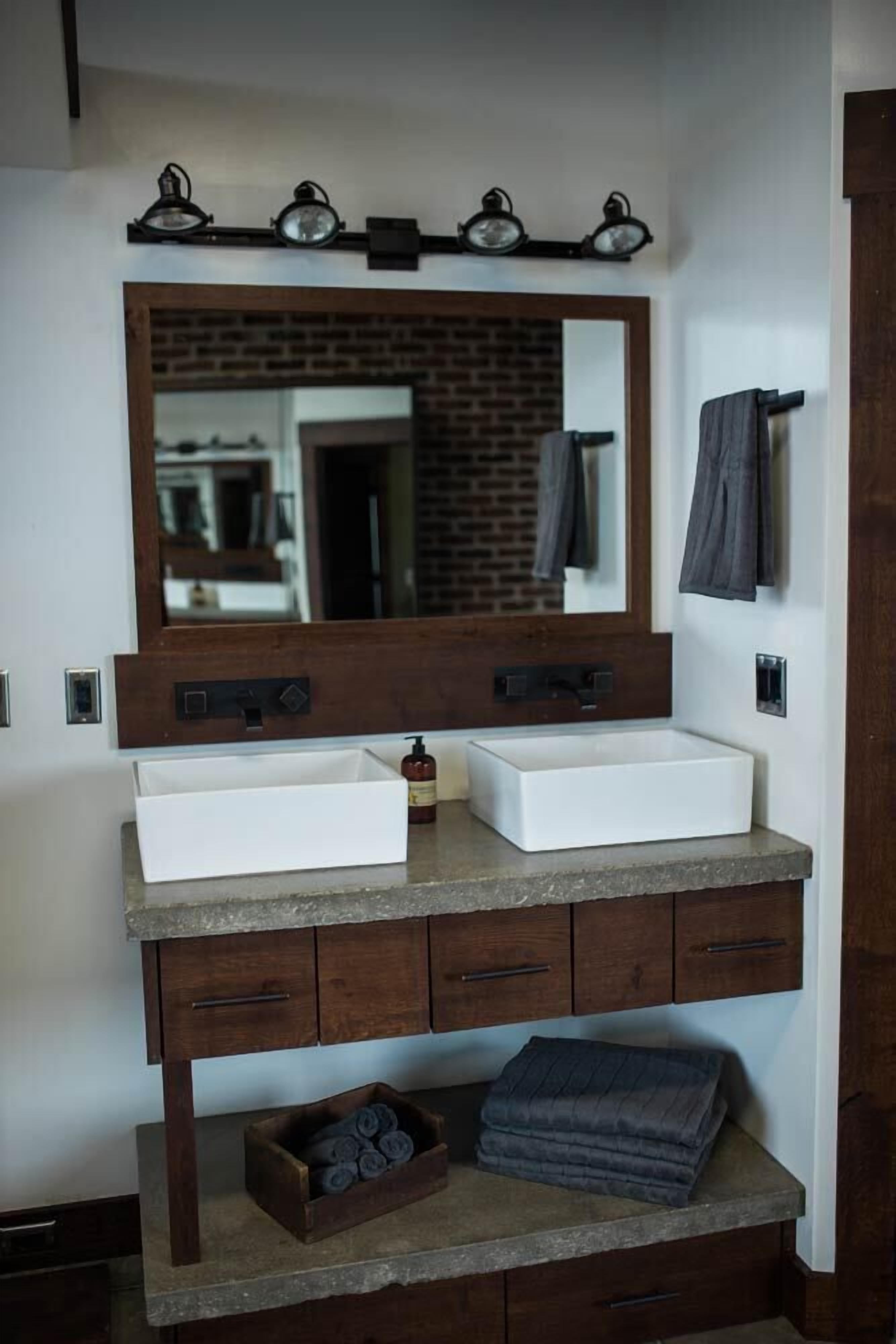 A bathroom with a double sink, a large mirror, and a wooden vanity.