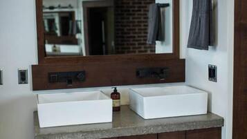 A bathroom with a double sink, a large mirror, and a wooden vanity.