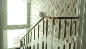 A staircase with a handrail and balusters, a chandelier, and patterned wallpaper. - Somerset Suites (Lagos)
