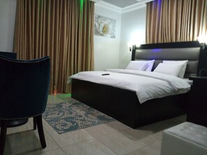 Una habitación de hotel con una cama, una silla y una mesita de noche.