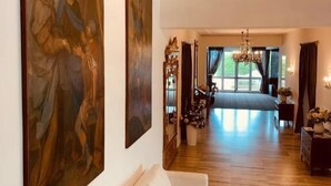 Una habitación amplia con una cama grande, un sofá blanco y dos cuadros de gran tamaño en la pared.