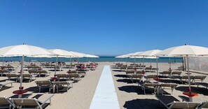A beachside hotel with rows of sun loungers and umbrellas, a white walkway leading to the sea, and a clear blue sky. - Hotel Miami Beach (Cervia)