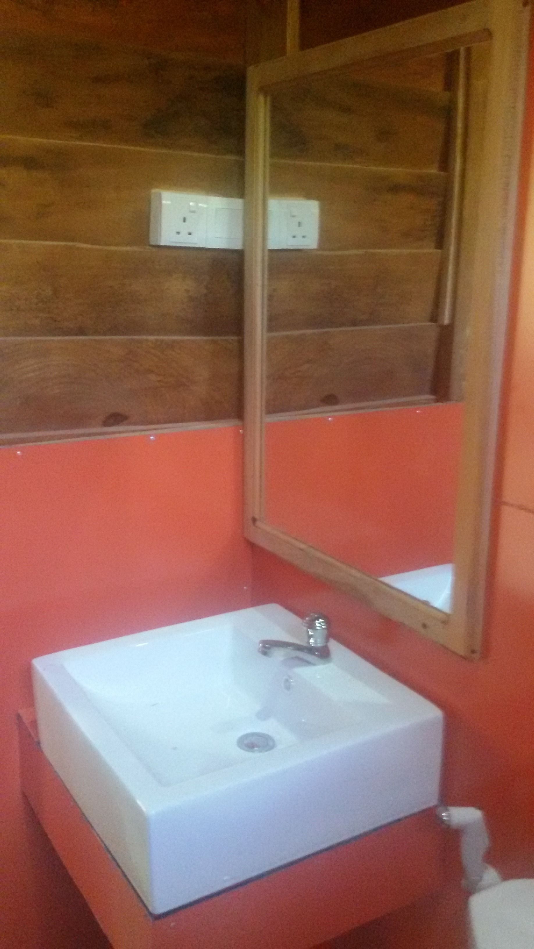 A bathroom with a white sink, a mirror, and a wooden wall.