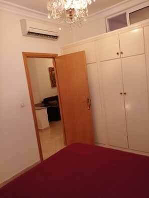 A bedroom with a bed, wardrobe, and a door leading to another room. - Furnished Appartement Malabata Beach (Tangier)