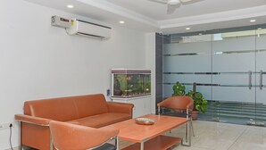 A modern living room with a sofa, a coffee table, and a fish tank. - Treebo Trip Vikrant's Residency (Gurugram)