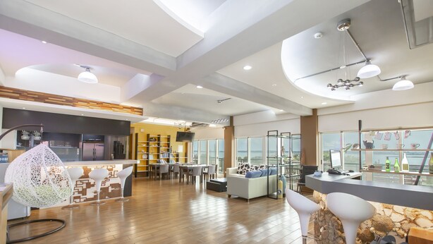A modern hotel lobby with a wooden floor, a reception desk, a dining area, and a seating area with unique chairs. - The Laid-back Dragon Lodge (Magong)
