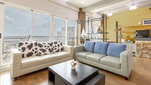 A modern living room with two sofas, a coffee table, and a large window offering a view of the city. - The Laid-back Dragon Lodge (Magong)