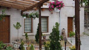 A courtyard with a pergola, potted plants, and a stone building with wooden doors and windows. - Days Inn Cappadocia (Nevsehir)