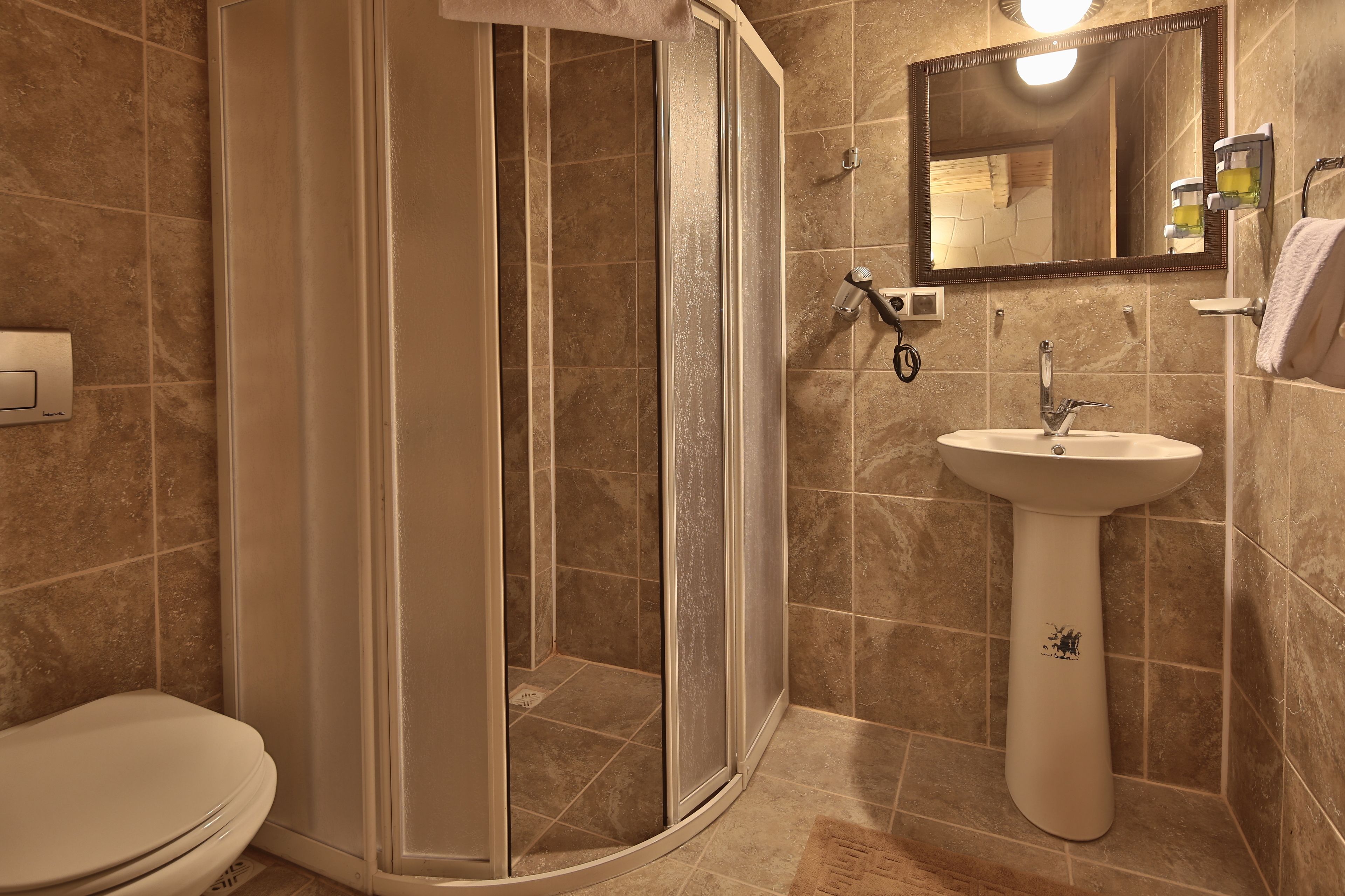 Un baño con cabina de ducha, lavamanos e inodoro.