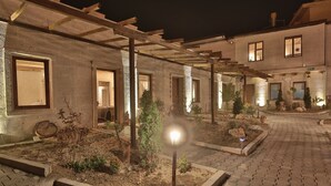 A courtyard with a pergola, stone walls, and a well-lit pathway. - Days Inn Cappadocia (Nevsehir)