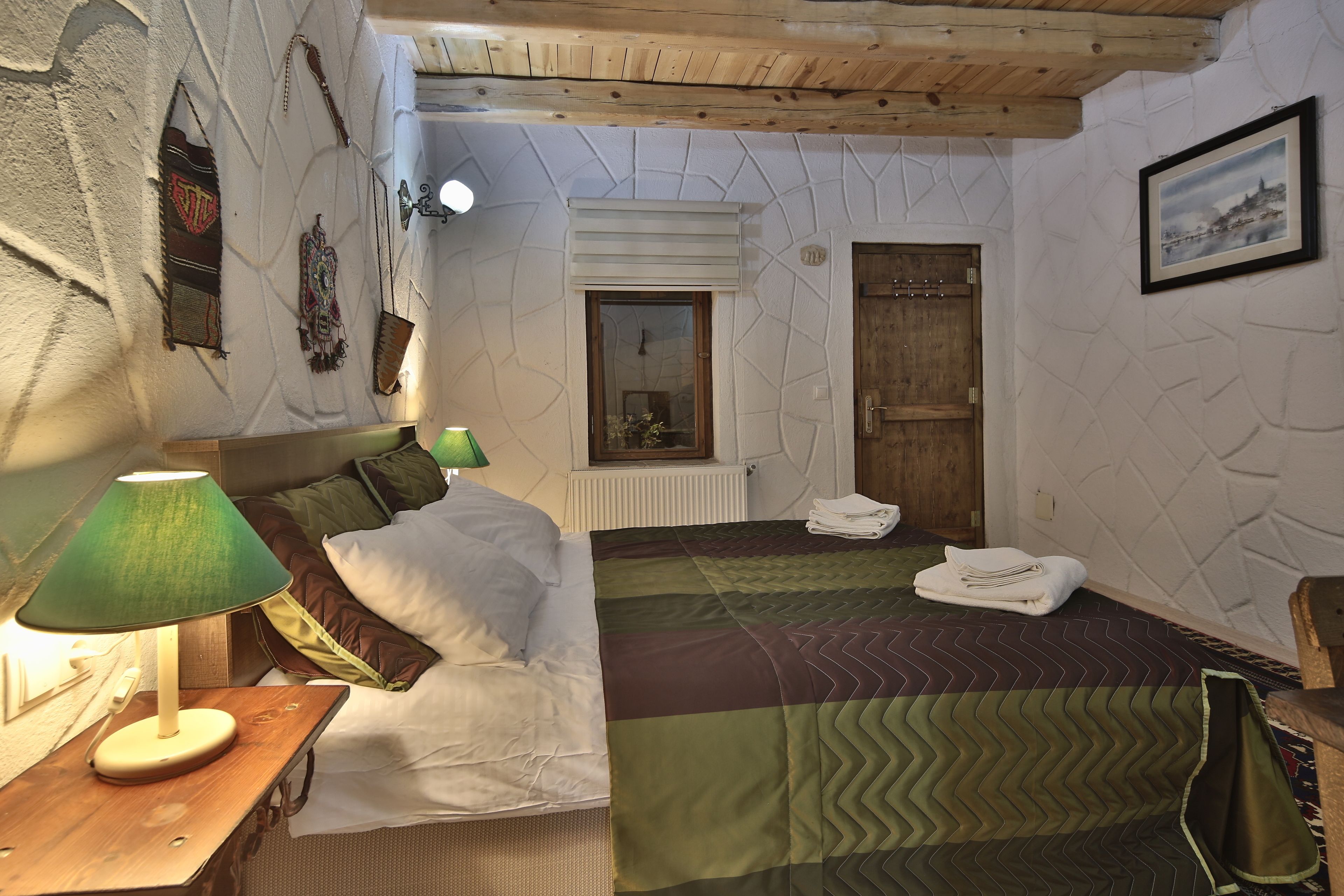 A room with a bed, a nightstand, a lamp, a window, and a door.
