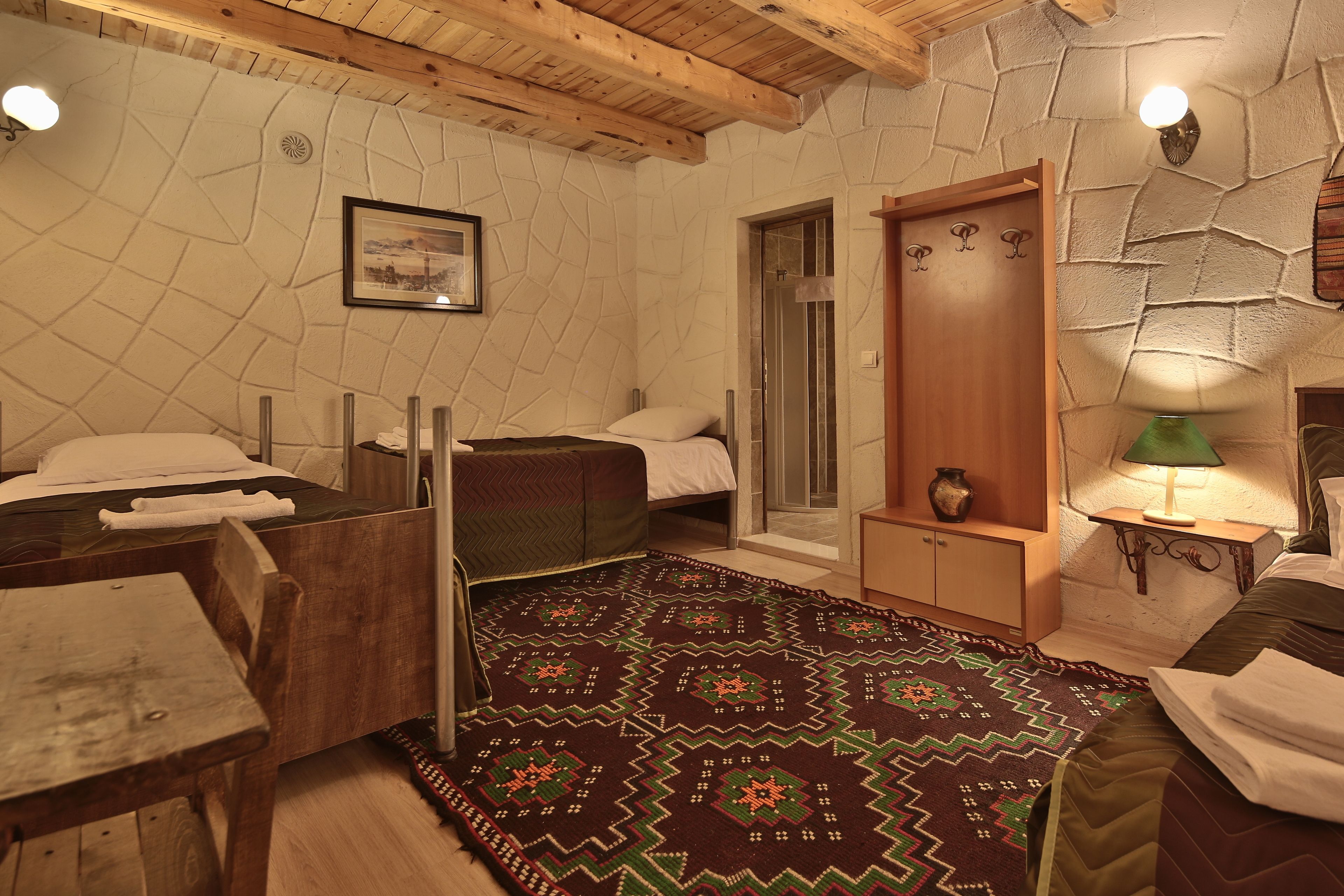 Una habitación acogedora con una cama, una mesa de madera, un banco y una alfombra estampada.