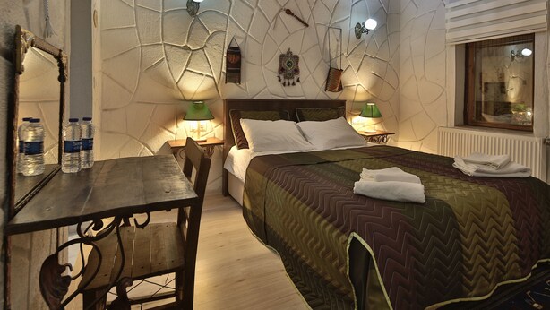 A bedroom with a bed, bedside lamps, a wooden table, and a mirror. - Days Inn Cappadocia (Nevsehir)