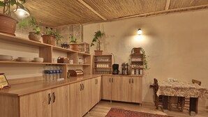 A kitchen with wooden cabinets, a dining table with chairs, and various kitchen items. - Days Inn Cappadocia (Nevsehir)