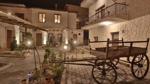 A courtyard with a wooden cart, potted plants, and a building with multiple windows and balconies. - Days Inn Cappadocia (Nevsehir)