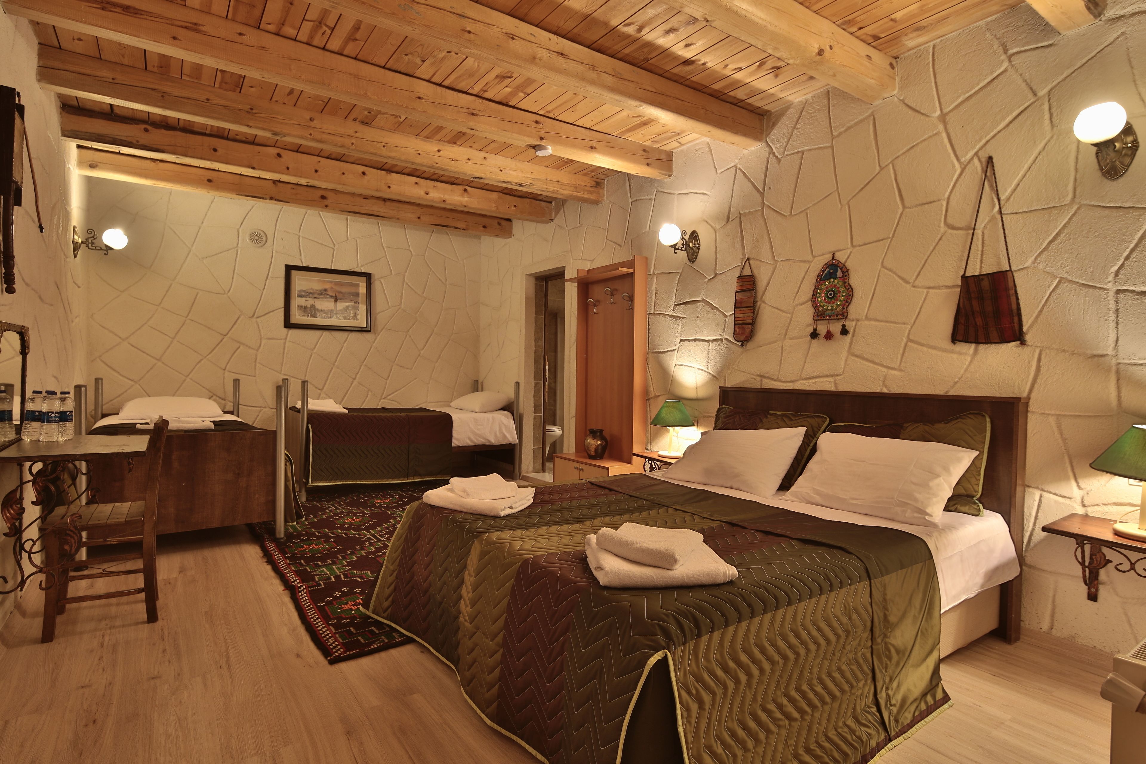 Una habitación de hotel con una cama grande, una cama más pequeña, un escritorio con silla y un baño.
