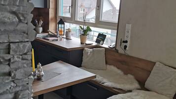 A modern kitchen with a large window, a stone wall, and a cozy seating area with a fluffy white rug.