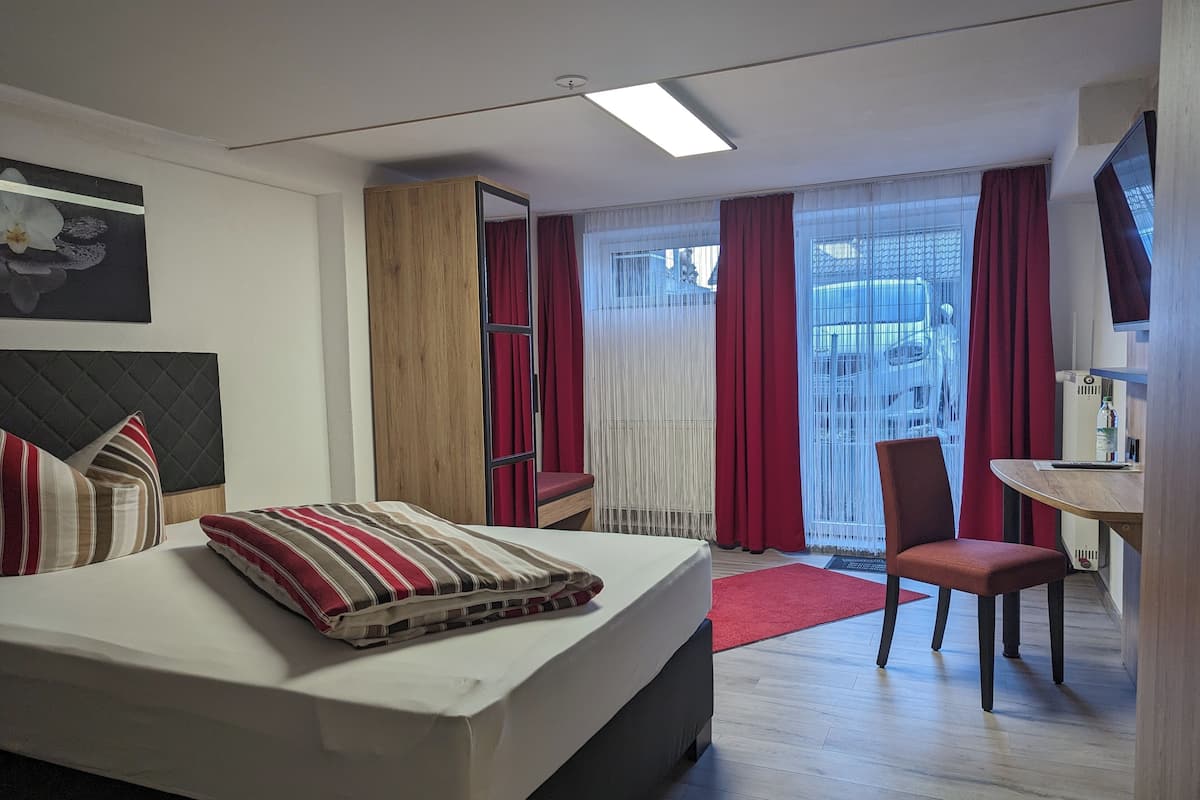Una habitación de hotel con cama, escritorio, silla y armario.