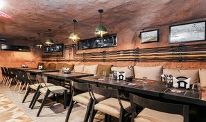 A restaurant with rustic decor, including exposed brick walls, metal pipes, and a long communal table with chairs. - Treebo Stay Tuned JP Nagar (Bengaluru)