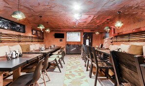 Un restaurante con una decoración rústica, que presenta paredes de ladrillo visto, mesas y sillas de madera, y lámparas colgantes.