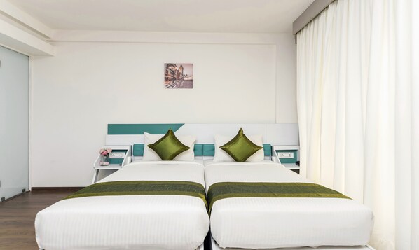 A hotel room with a bed, a nightstand, and a small table with a vase of flowers.