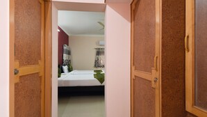 A bedroom with a bed, a ceiling fan, and a window with curtains. - Itsy Hotels Shivas Kuteera (Bengaluru)