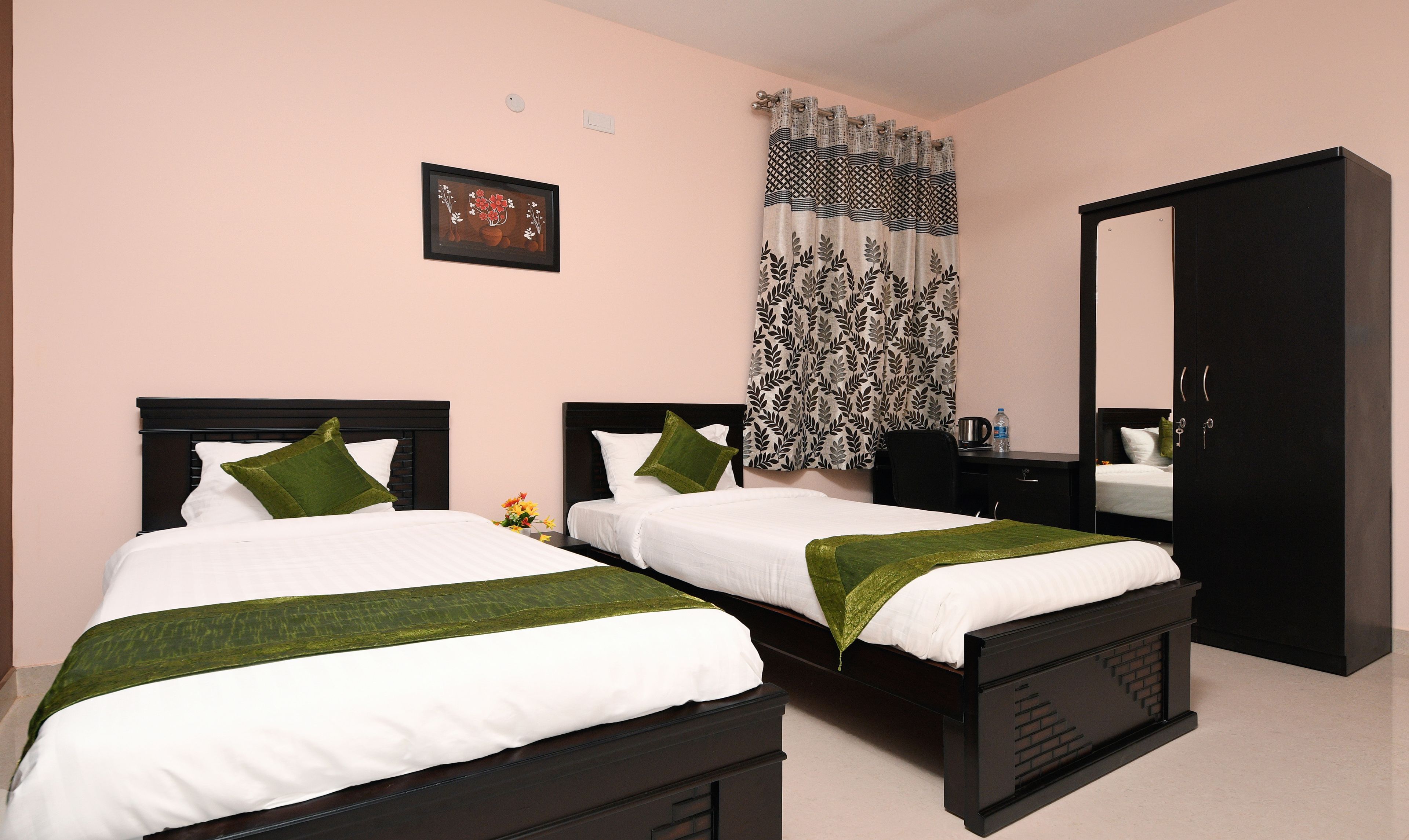 A hotel room with two beds, a desk, a wardrobe, and a bathroom.