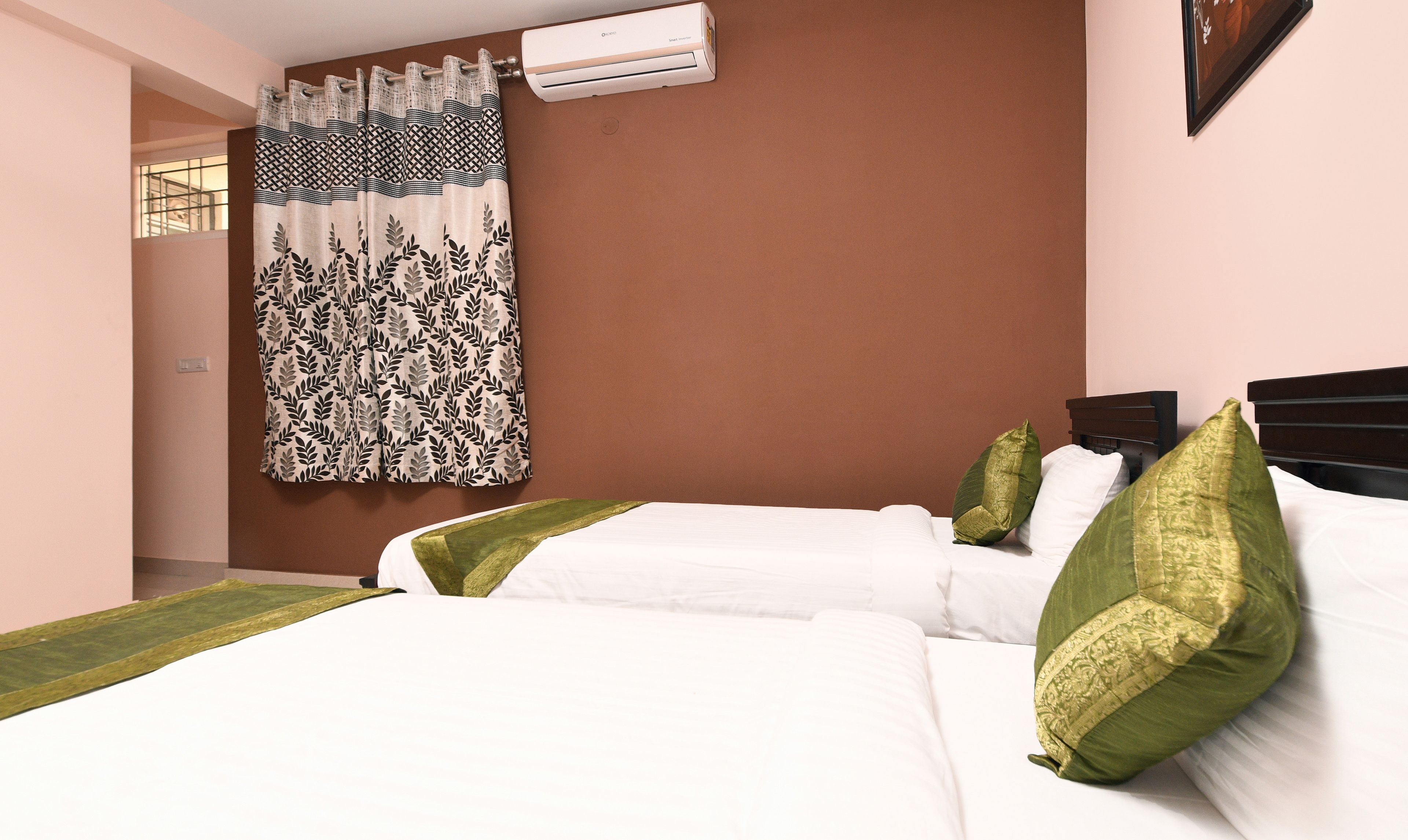 A hotel room with two beds, a large window with a view, and an air conditioning unit on the wall.