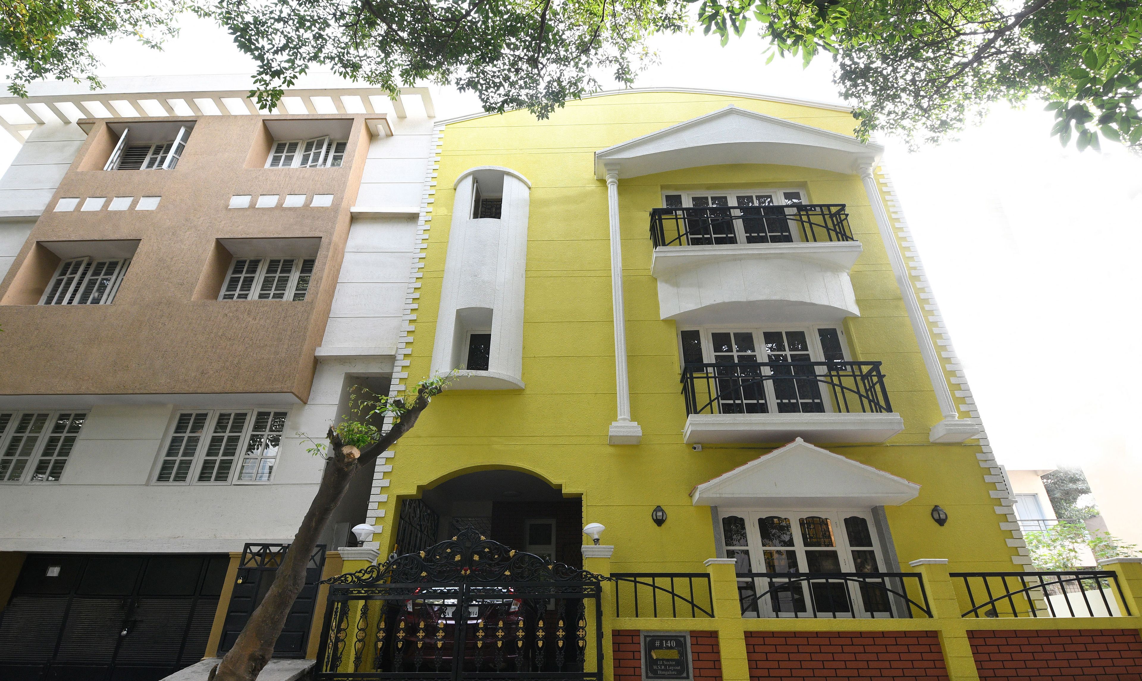A multi-story building with a yellow facade, white trim, and a black gate.